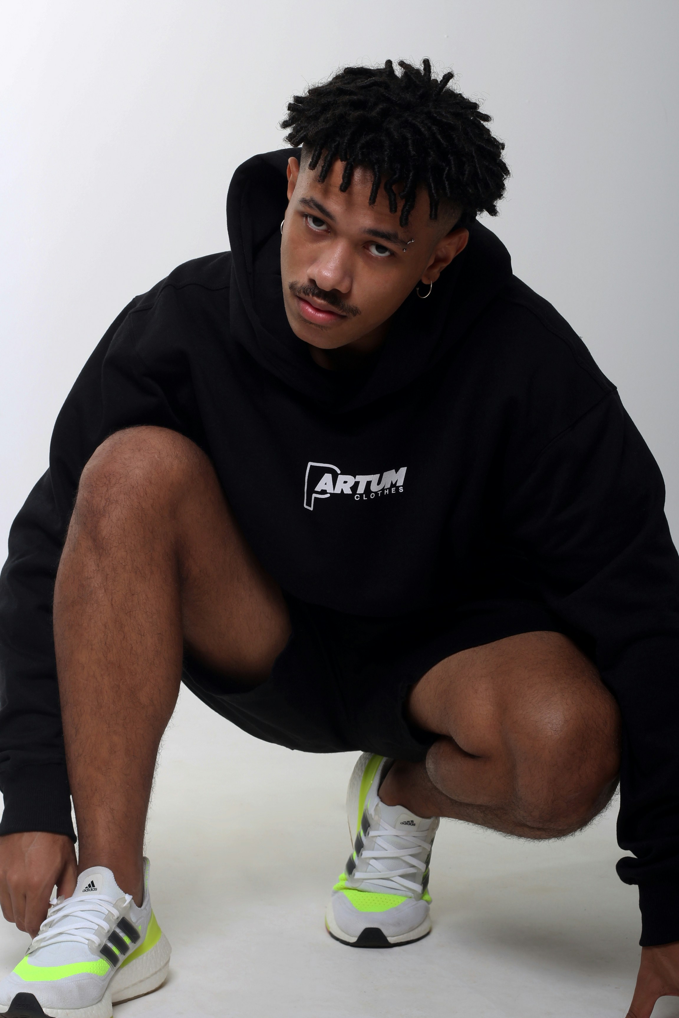 Model in black hoodie and neon-accent sneakers
